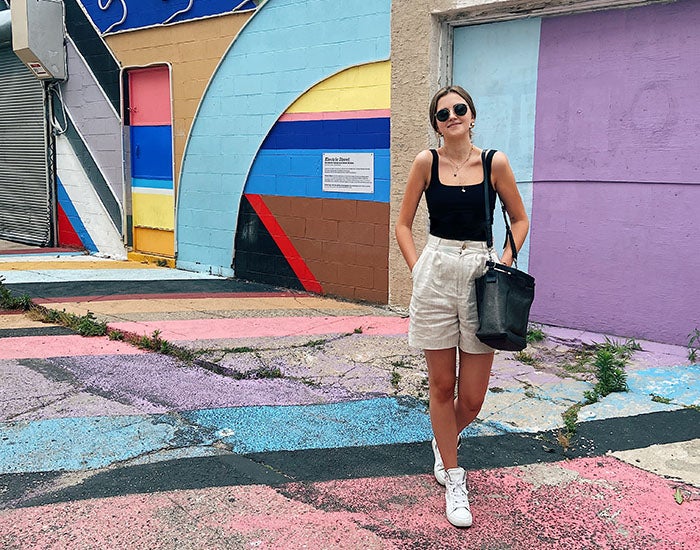 Anna Callahan standing in front of a building painted in bright colorblocks. The street is also painted.