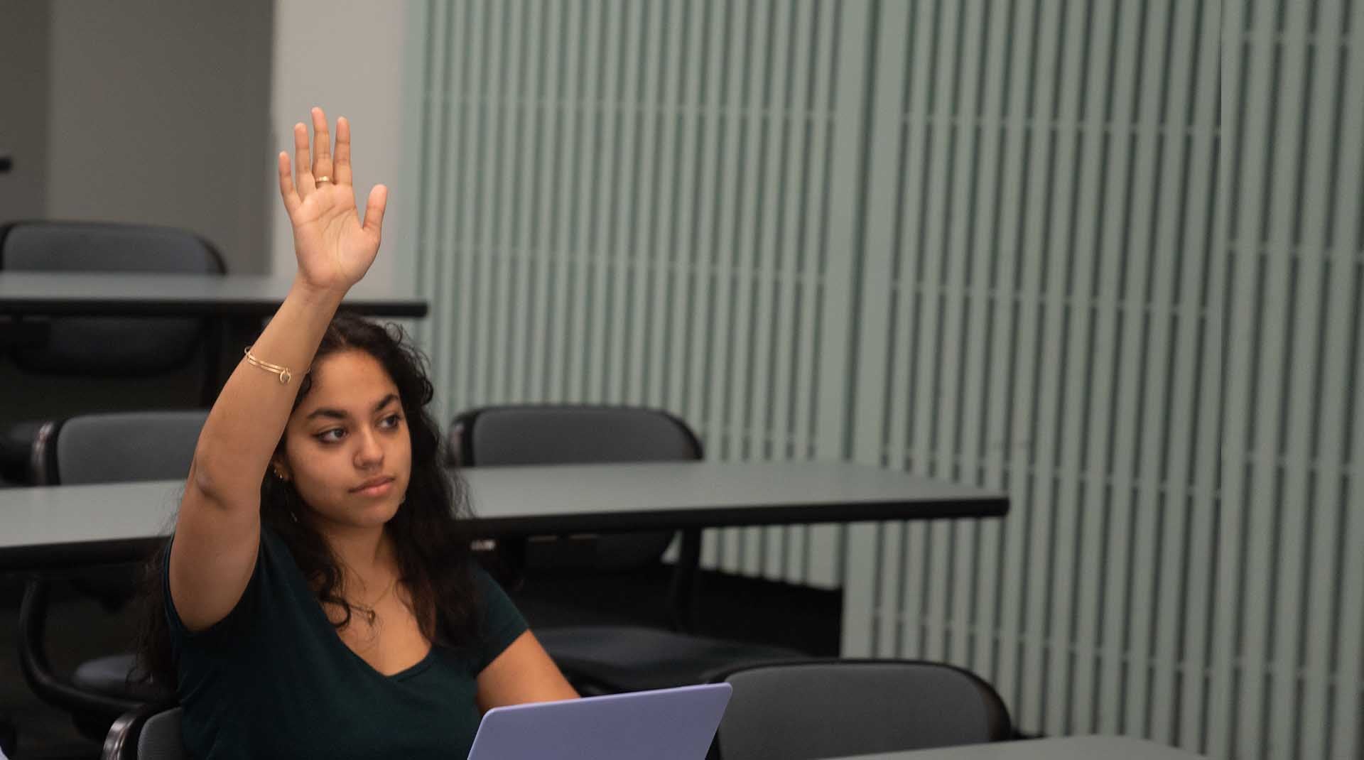 Student with their hand raised in a classroom